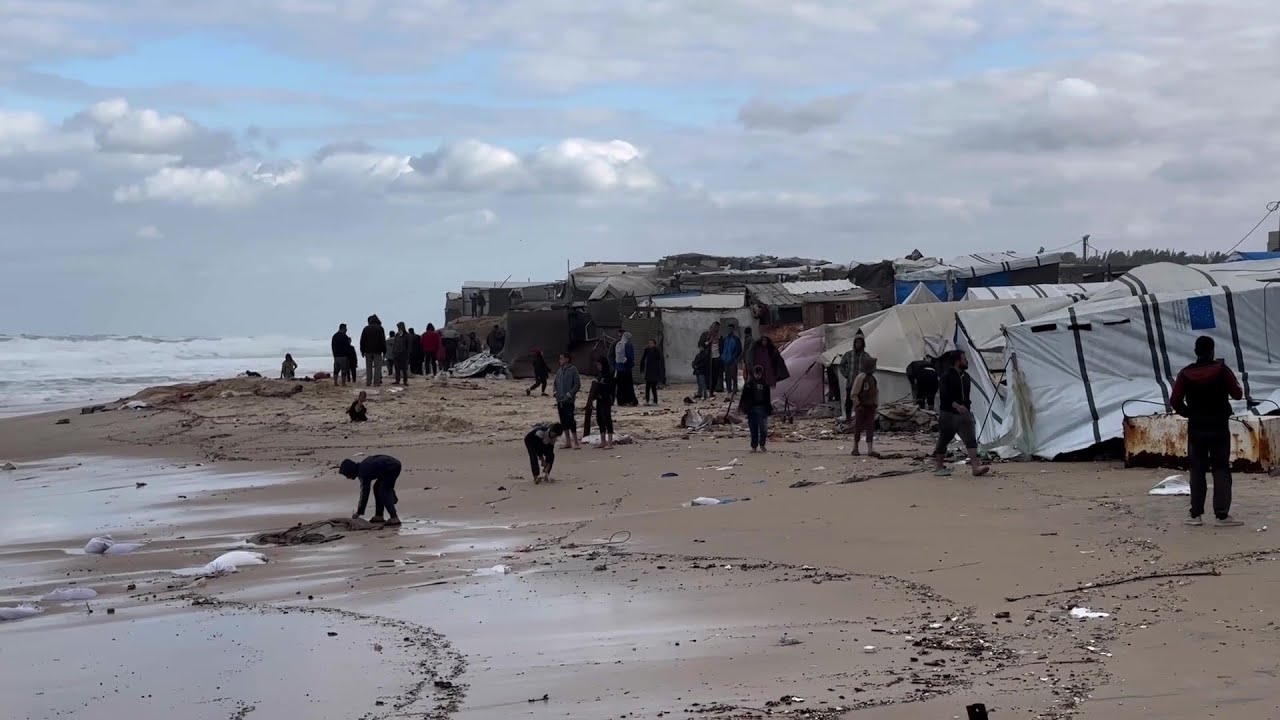 نازحون فلسطينيون يتفقدون خيامهم التي غمرتها مياه المدّ البحري على طول شاطئ دير البلح وسط قطاع غزة