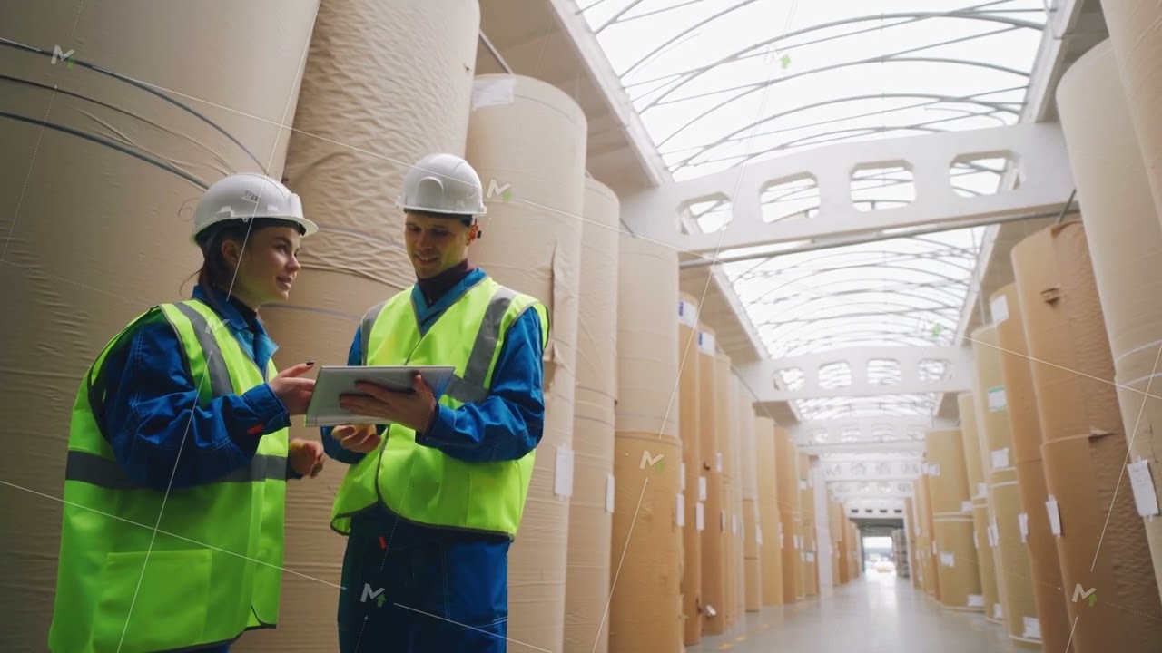 Warehouse of a paper factory. Rolls of paper, engineers enter data into a tablet