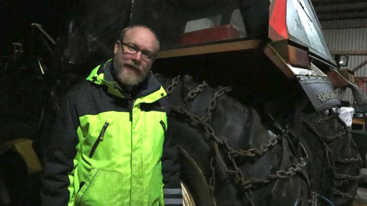 Monterar snökedjor på traktorn