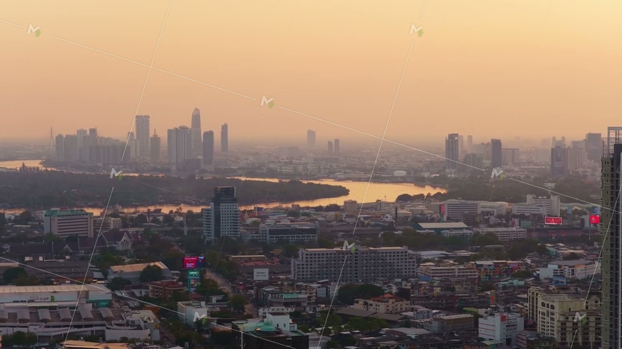 Aerial view of Bangkok's urban skyline with the Chao Phraya River reflecting warm glow of sunset