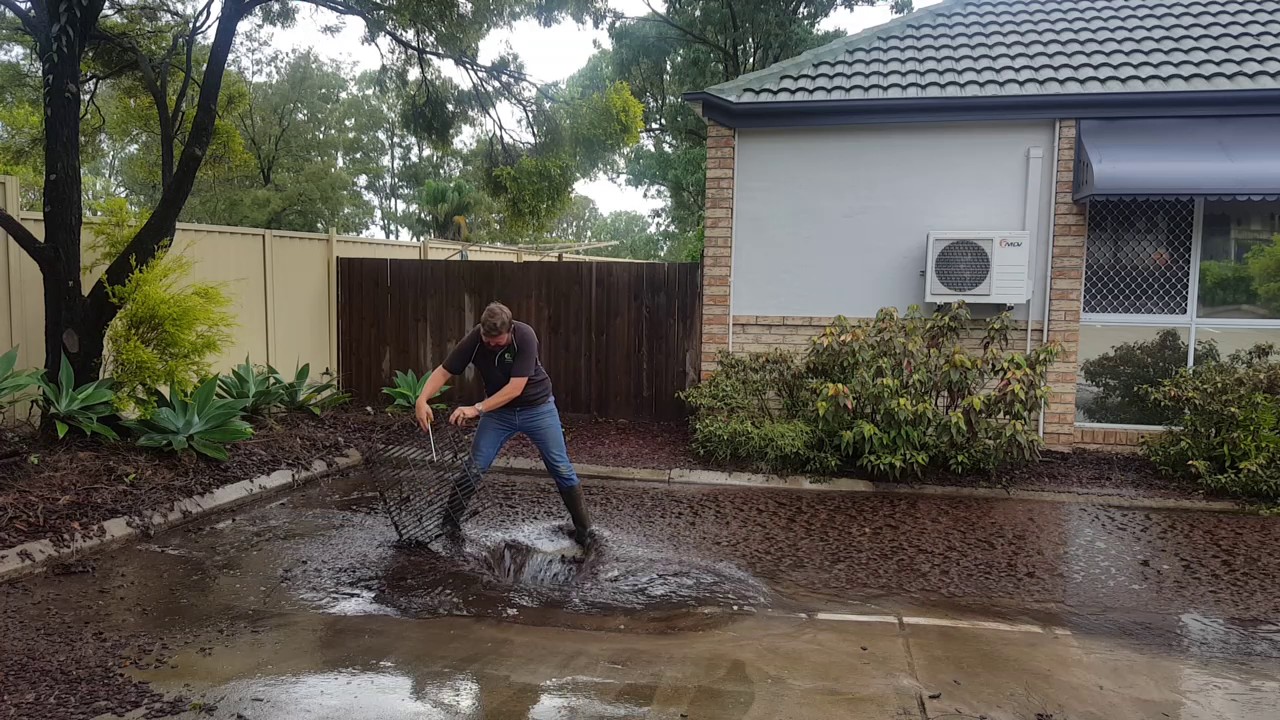 Plumber clearing a blocked grate after storm