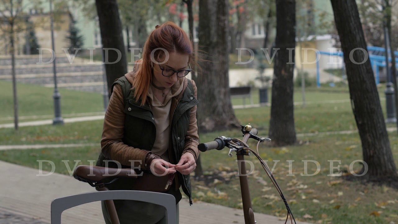 Woman cyclist opening lock on bicycle parking in city park