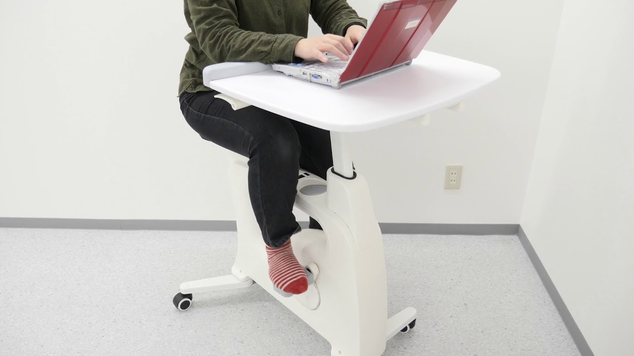 FlexiSpot Deskcise Pro デスクバイクV9に座って作業をしながらペダルをこぐ様子