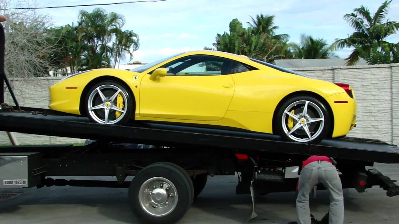 yellow Ferrari 458 Italia being loaded on a tow truck