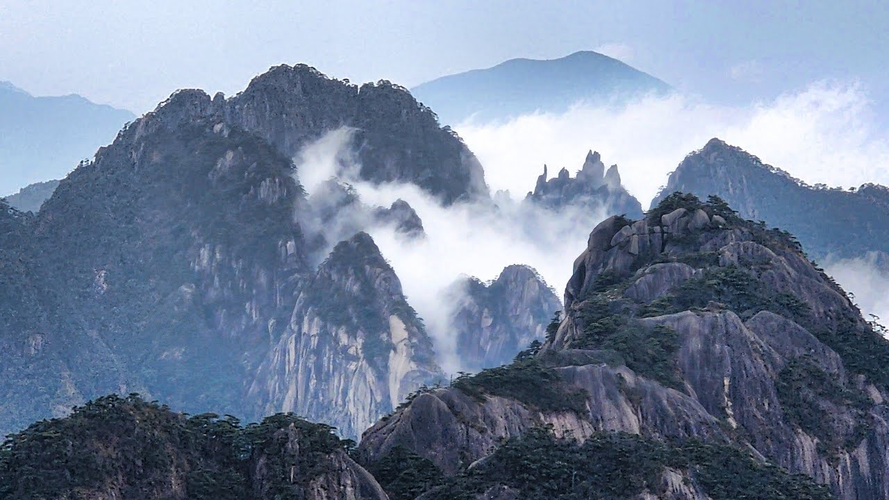 黃山，以奇松、怪石、雲海著稱。雲霧在峰巒間流動，日出時金光灑滿山谷，宛如一幅會呼吸的畫。迎客松屹立山巔，象徵黃山的精神與魅力。黃山歸來不看山。