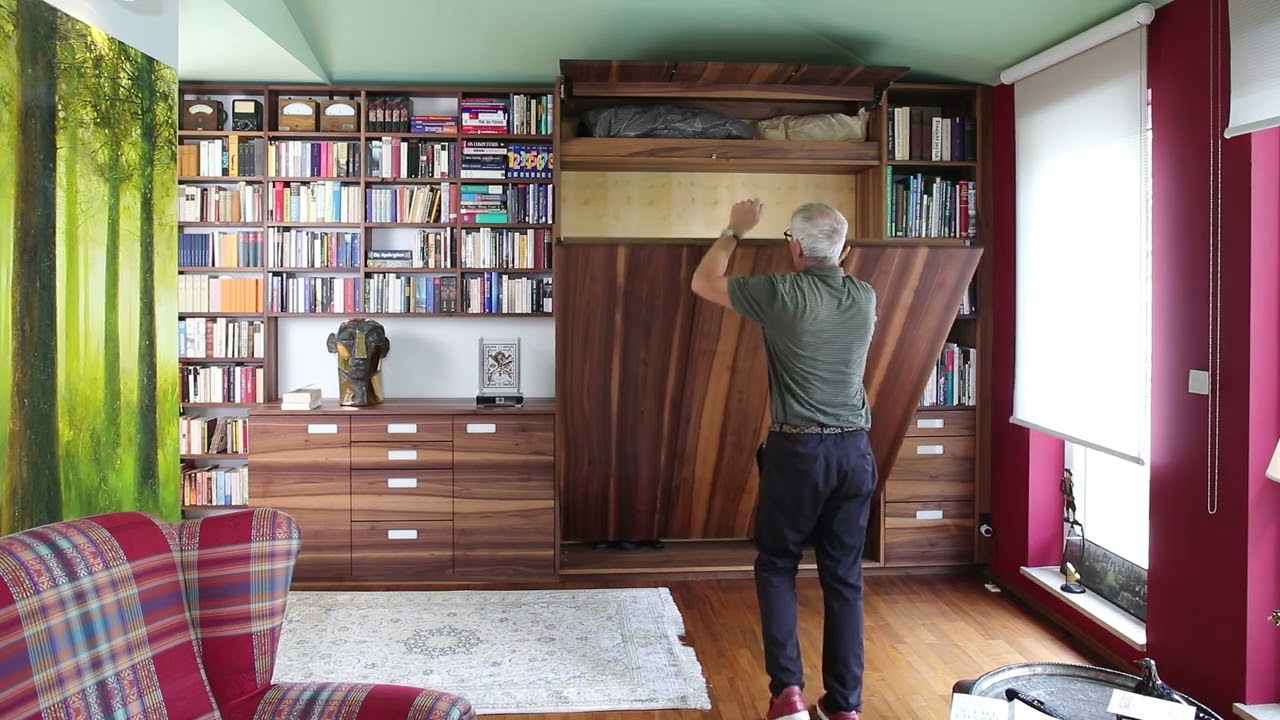 Klappbett in einer Bücherwand mit Sideboard in Nussbaum