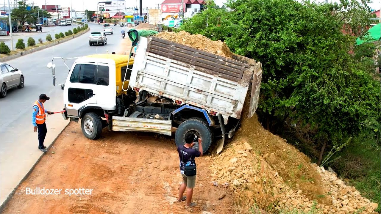 Dump truck 5T unloading soil landfilling up with bulldozer working push soil filling flooded area 