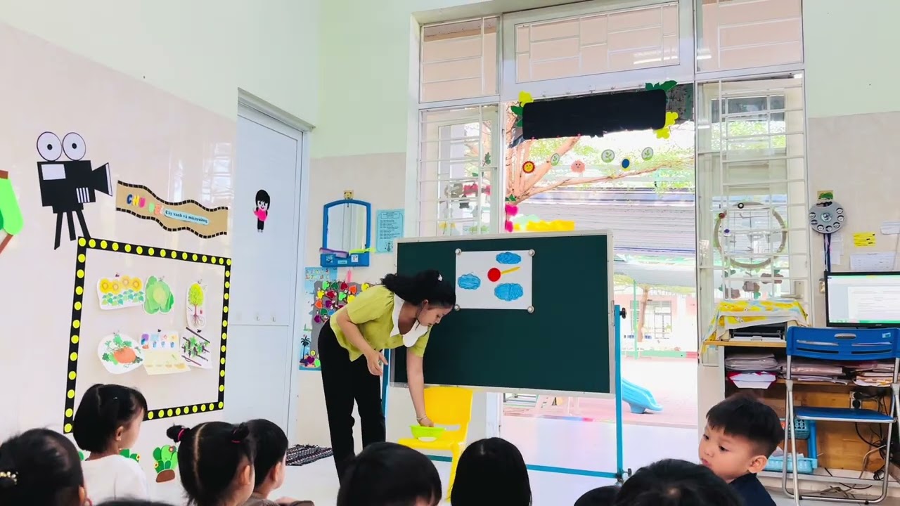 Cô hướng dẫn bé cắt, dán ông mặt trời