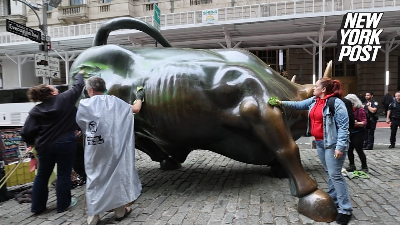 Wall Street Bull painted on by environmental activists, frantically clean it up when cops come