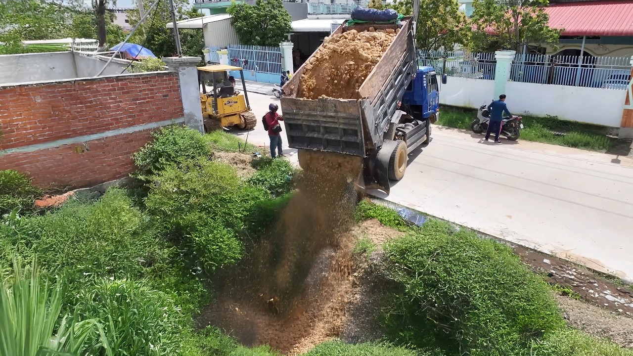 New project shows Komatsu D20P using professional drivers to push backfill into lake