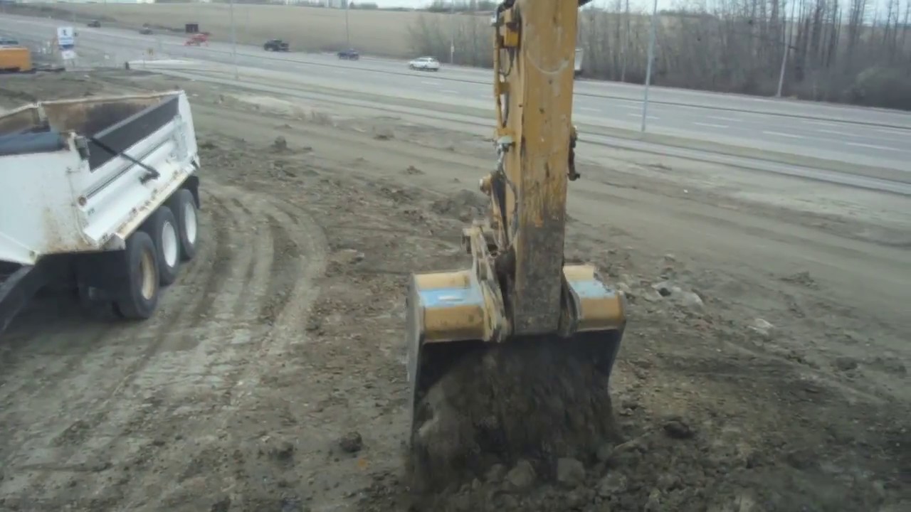 Cat 320 loading frozen clay on trucks - cab view