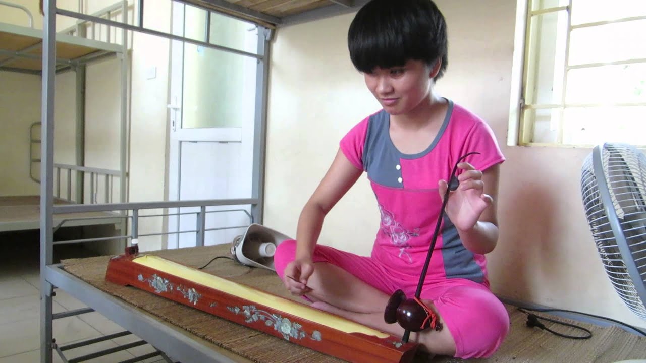 Vietnamese student plays the đàn bầu (traditional instrument)