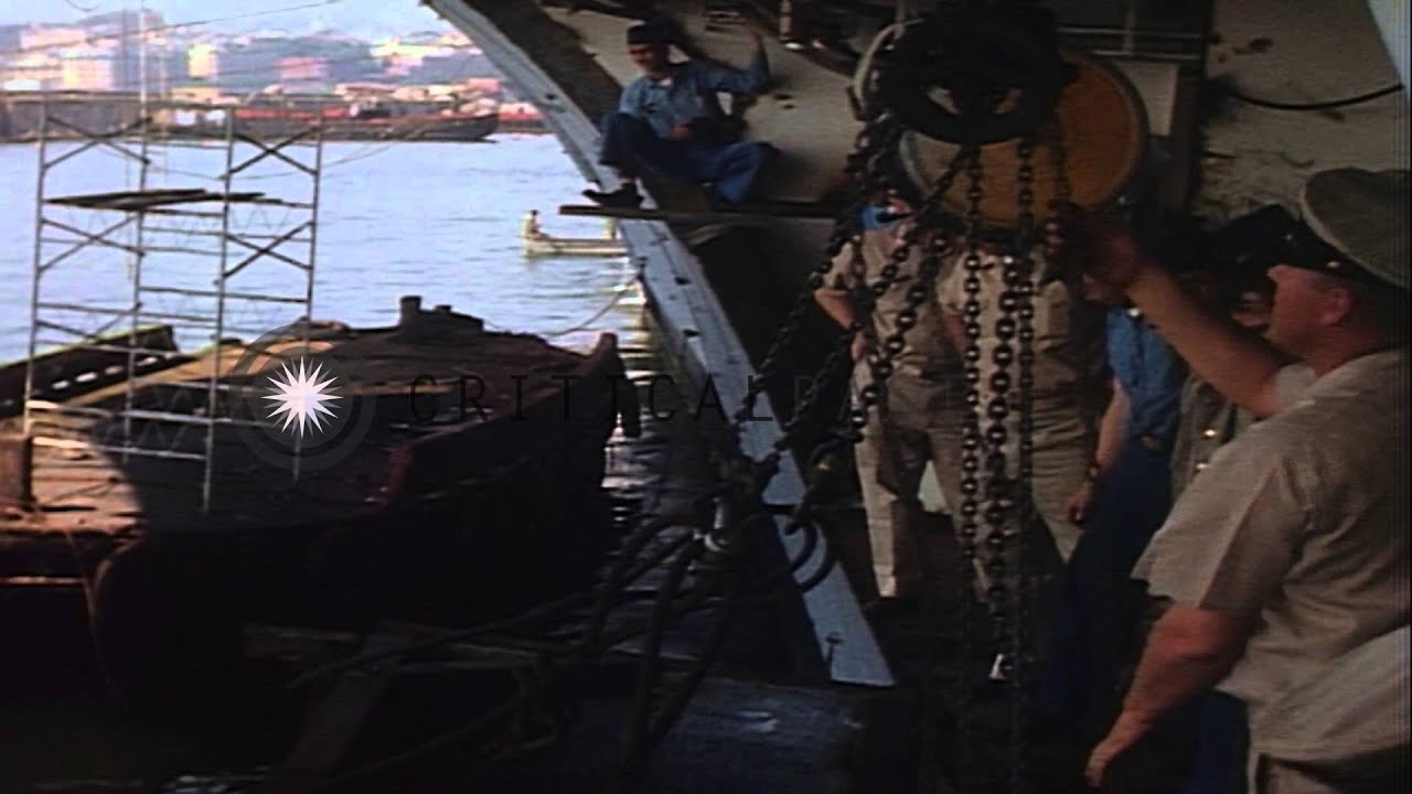 A cofferdam is hoisted up alongside Shangri La, half in the water and men pull it...HD Stock Footage