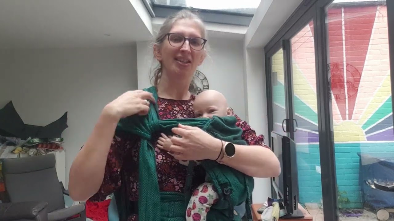 Robins hip carry with a half buckle baby carrier. Shown with the Lenny Lamb Hybrid.