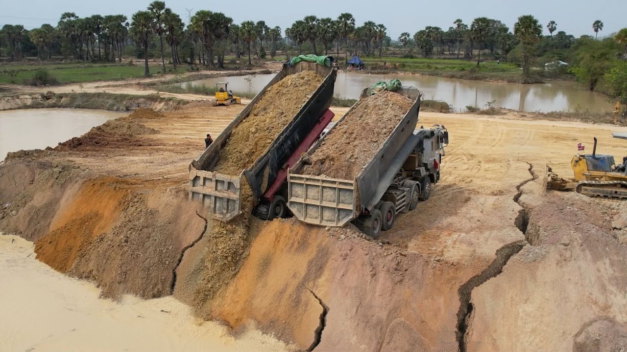 incredible power of a dozer and multiple dump trucks are filling the pond
