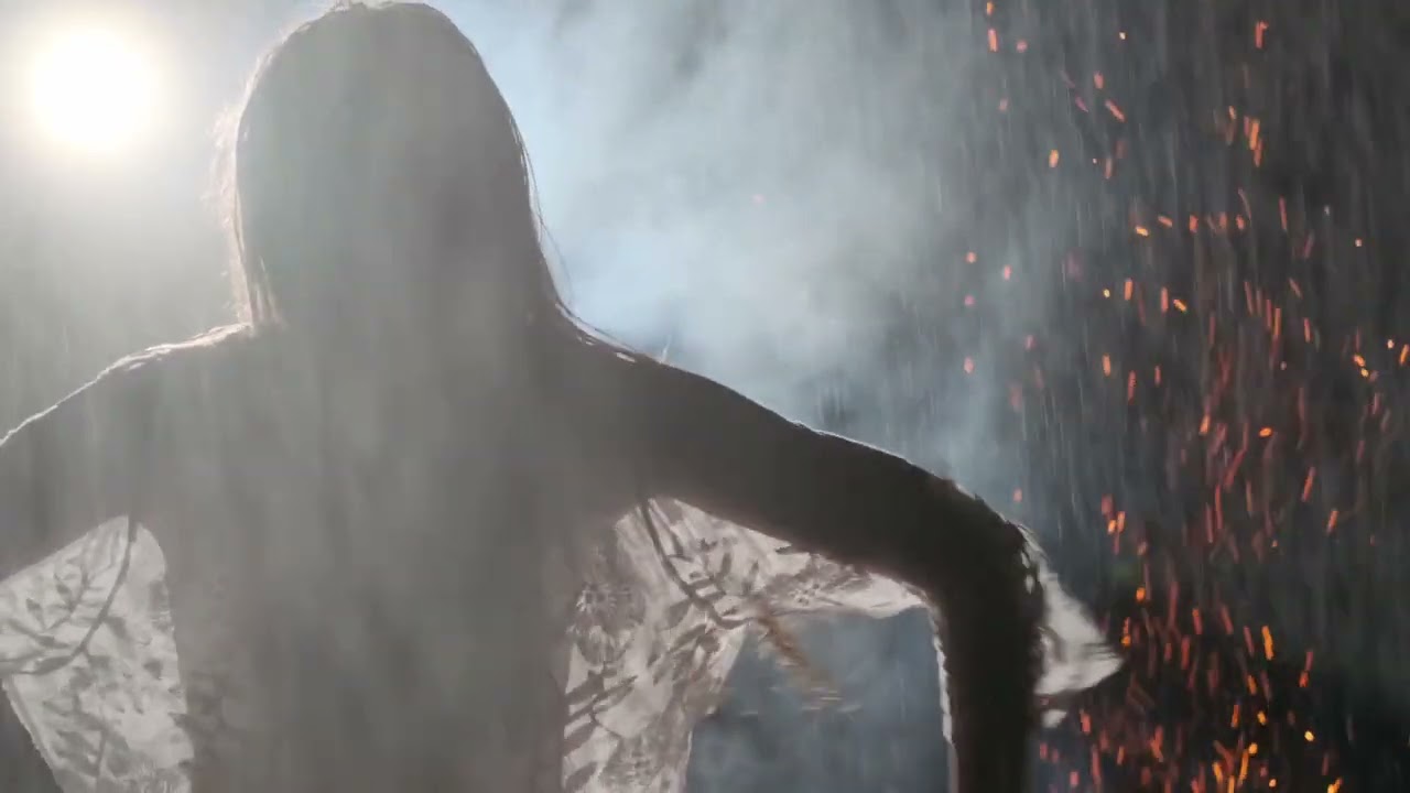 Woman Silhouette Dancing at Night among Sparks and Rain.