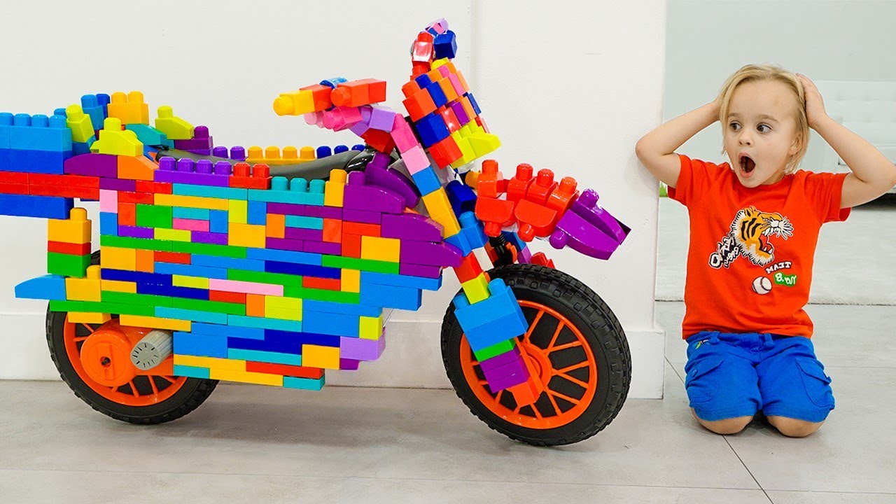 Chris monte sur une moto de sport et joue avec des jouets