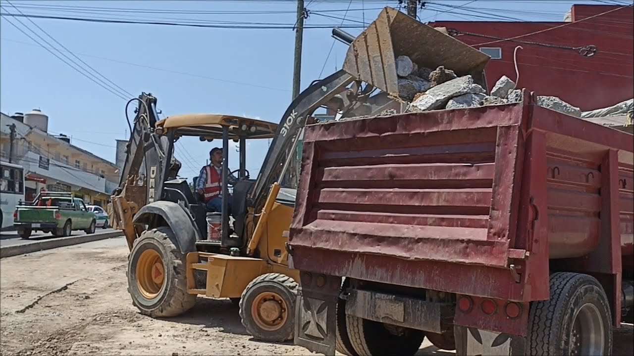 Retroexcavadora John Deere 310K cargando camiones de volteo y moviendo material