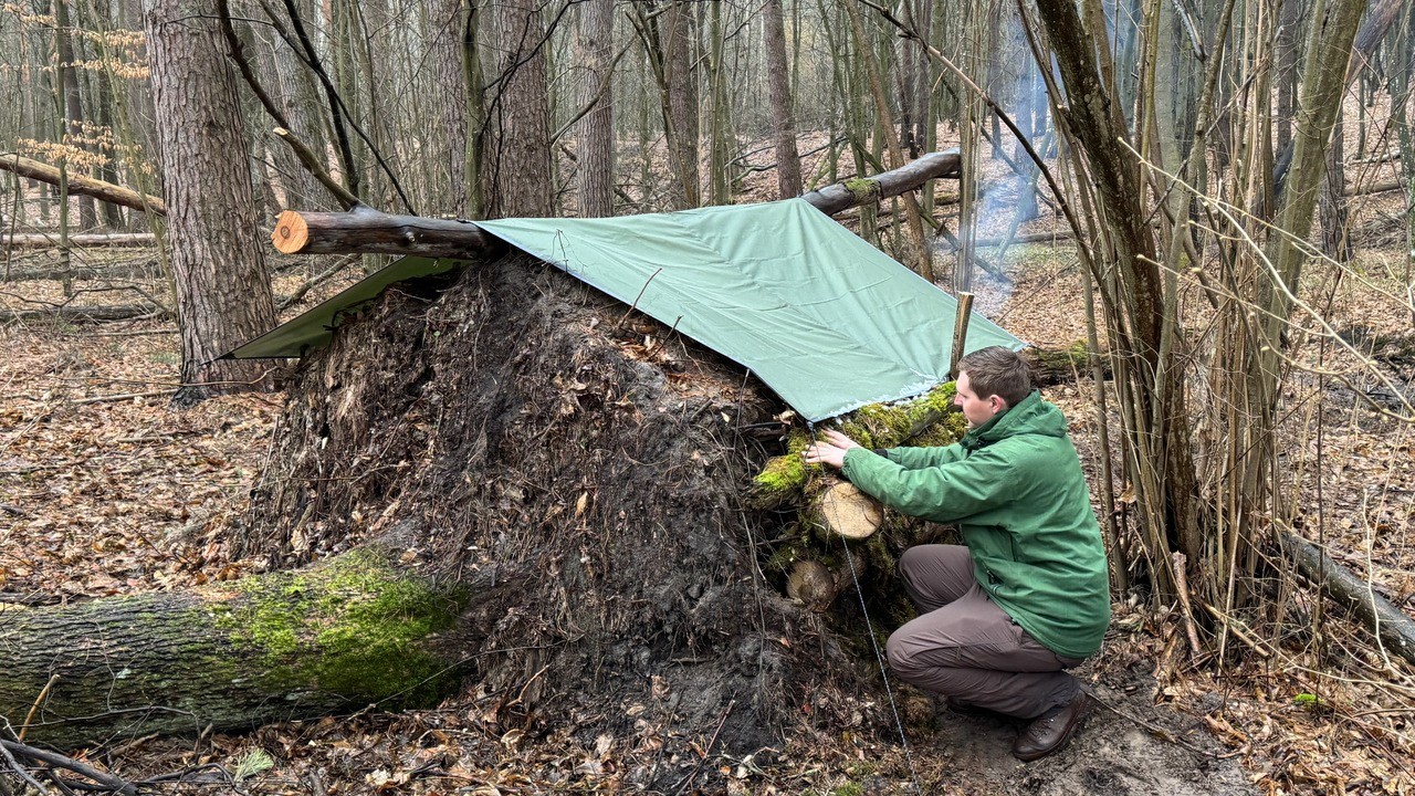 Building a shelter in the root of a fallen oak tree in heavy rain and snow. Cooking on a fire.