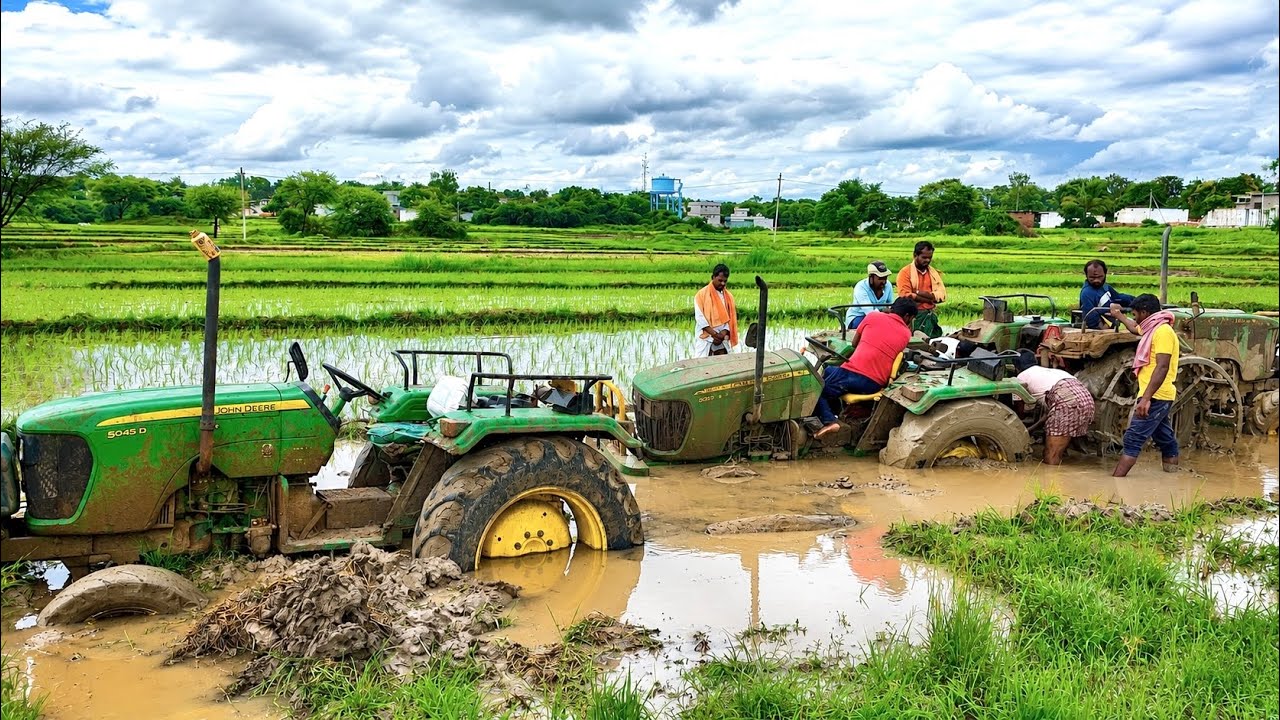 John Deere tractors stuck in mud pulling by another John Deere tractor