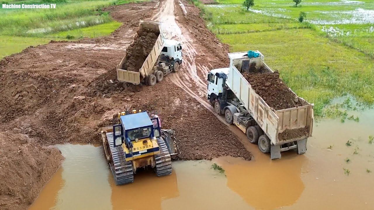 Heavy Bulldozer Komat'su D58P and Many Dump Trucks 25T Unloading Soil Make New Road on Flooded Area