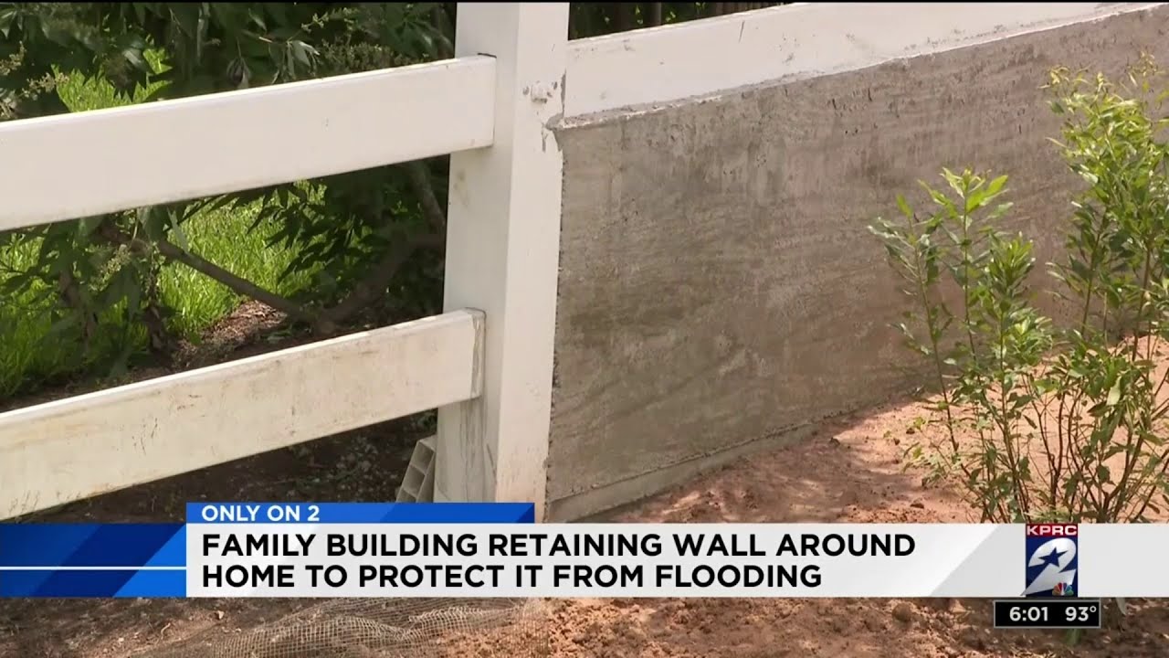 Family building retaining wall around home to protect it from flooding