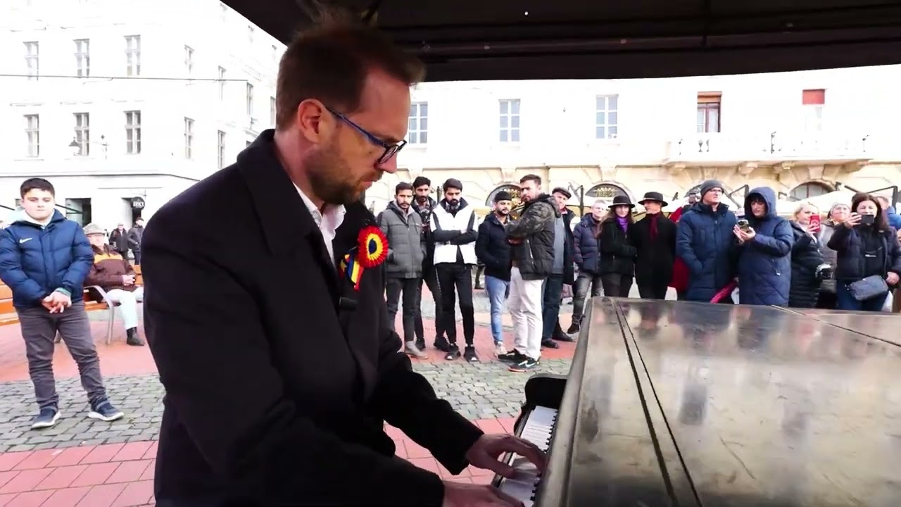 Dominic Fritz cântă imnul României la pian, în Piața Libertății din Timișoara.