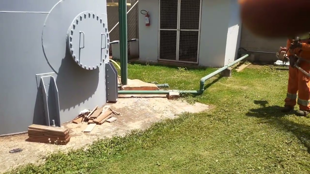 Eu estou mostrando o meu irmão roçando a grama esmeralda envolta da caixa d'água