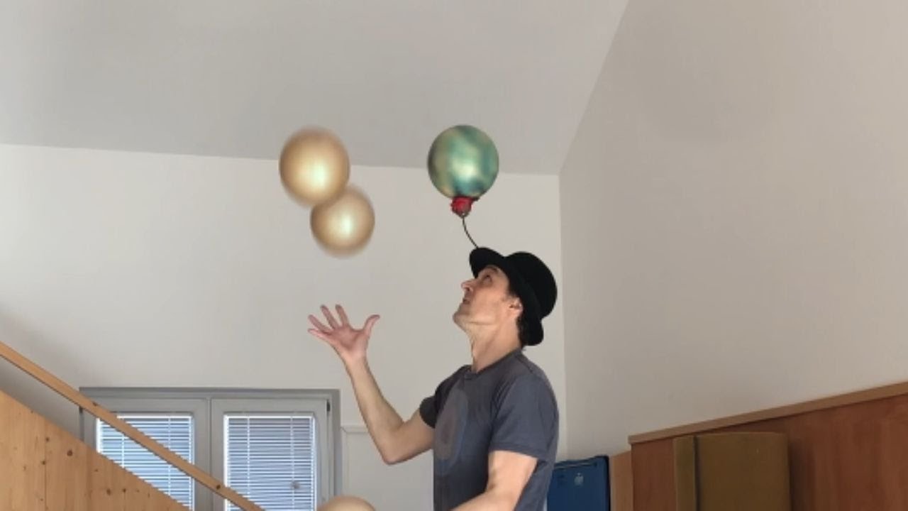Juglar impressively juggles 5 balls balancing atop 3 Rola-bola  while spining a ball on hat