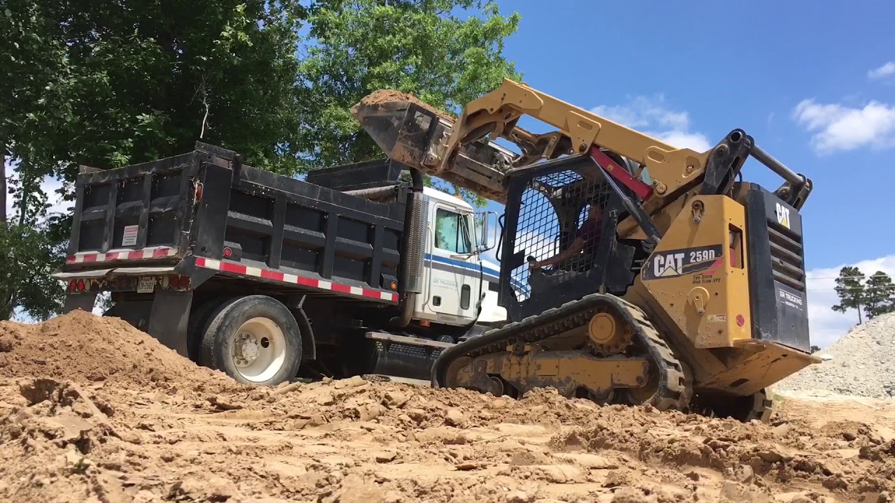 Caterpillar 259D skid steer loading dump truck with dirt