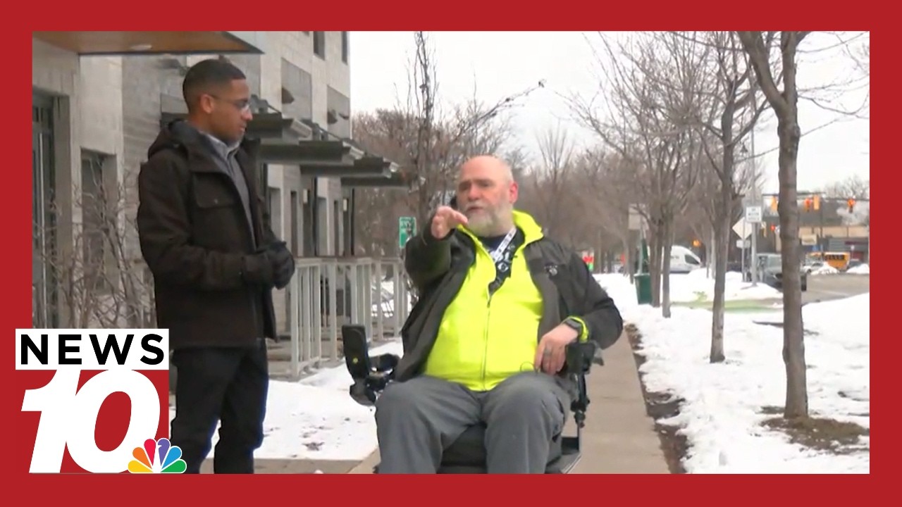 Firefighters help man in a wheelchair get unstuck from a snow-covered sidewalk