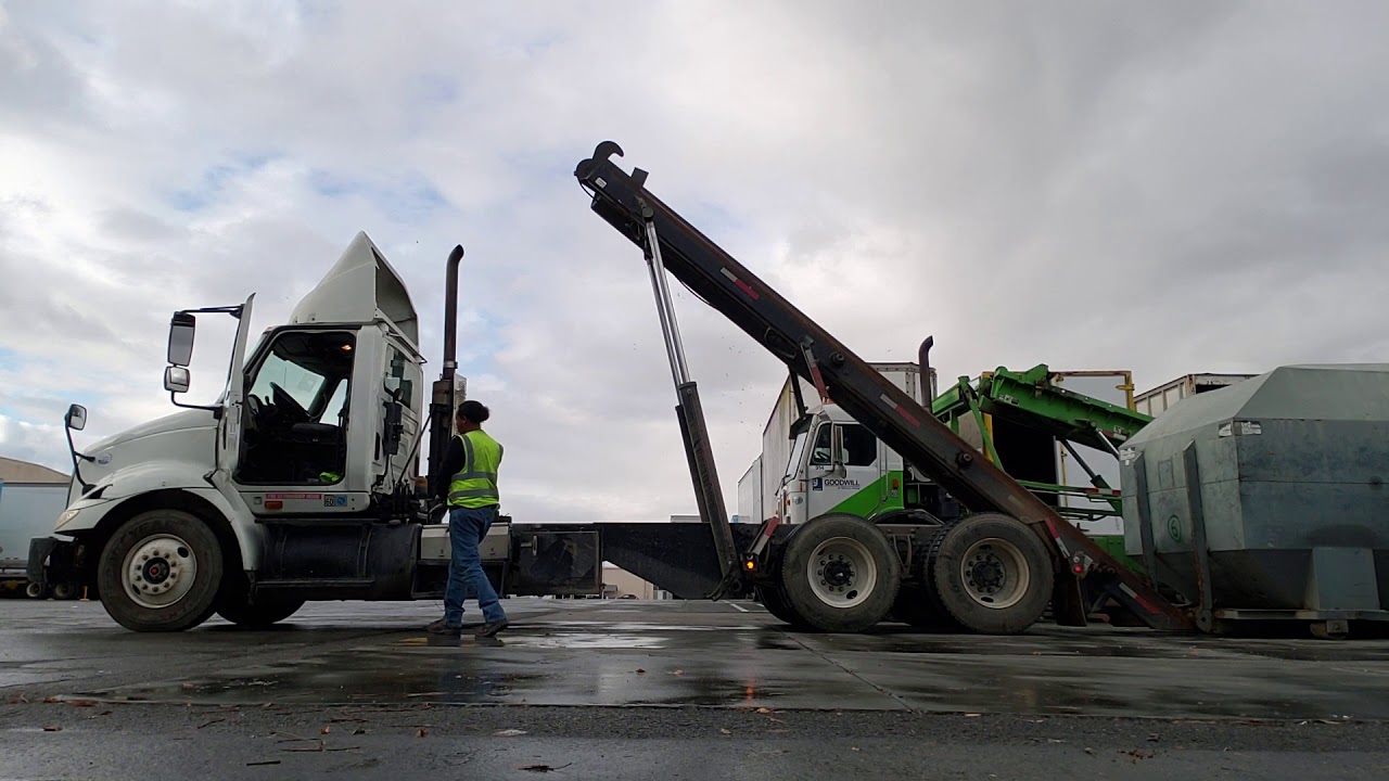 Roll off truck, loading compactor bin.