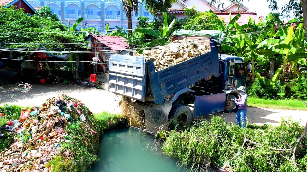 Delete pond with excellent bulldozer D31P and dump truck 5 ton drop the stone into the water