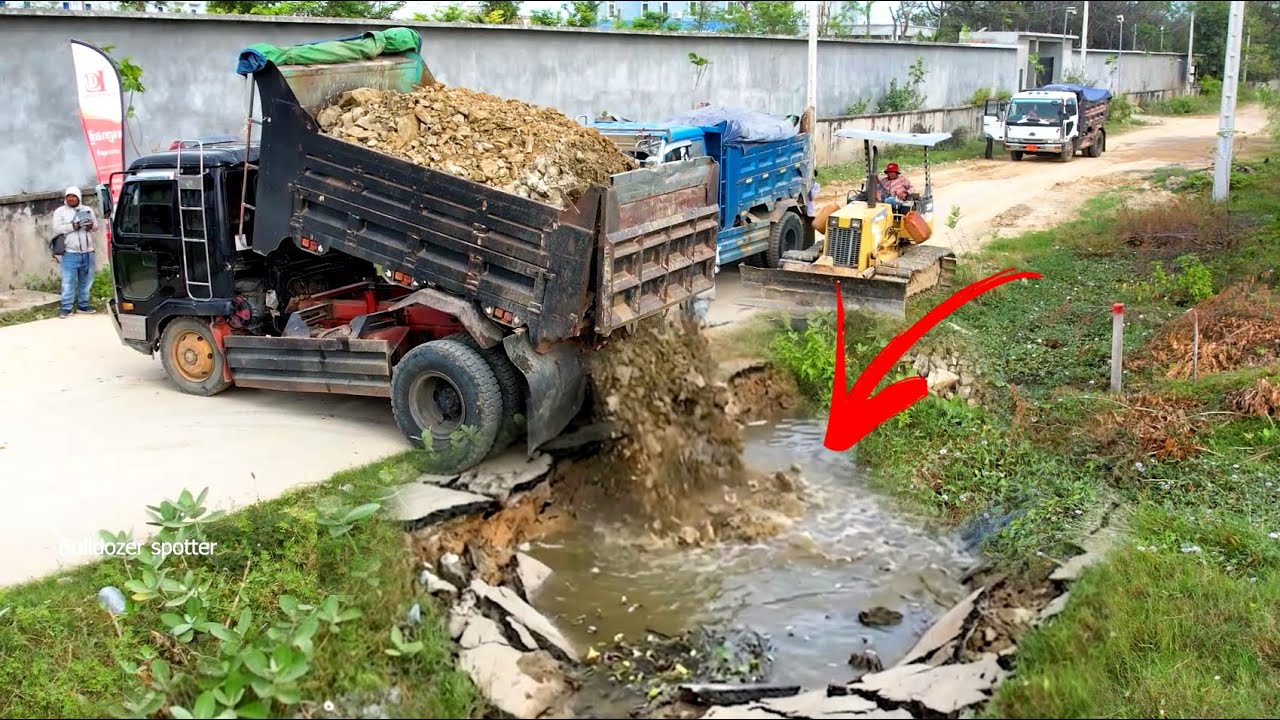 Great job !! Dump truck unloading Rock landfill flooded with Bulldozer D20P working push filling up 