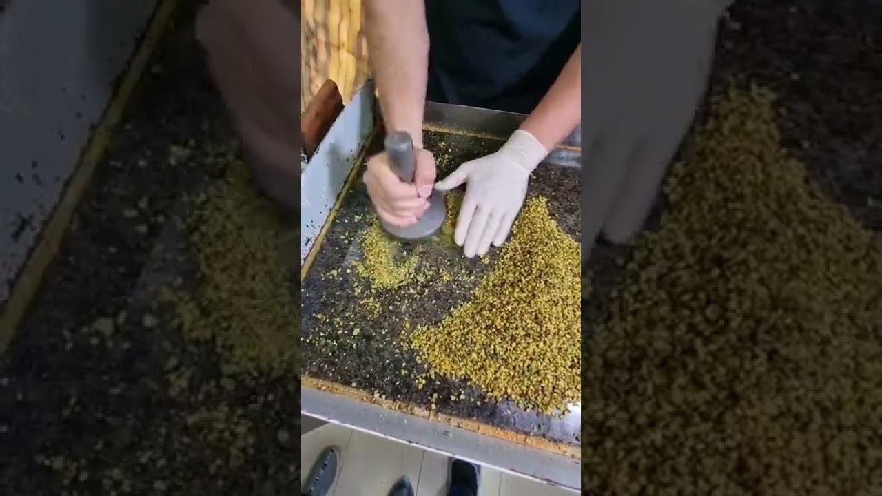 Pounding and crushing the pistachio kernels for Sohan sweets