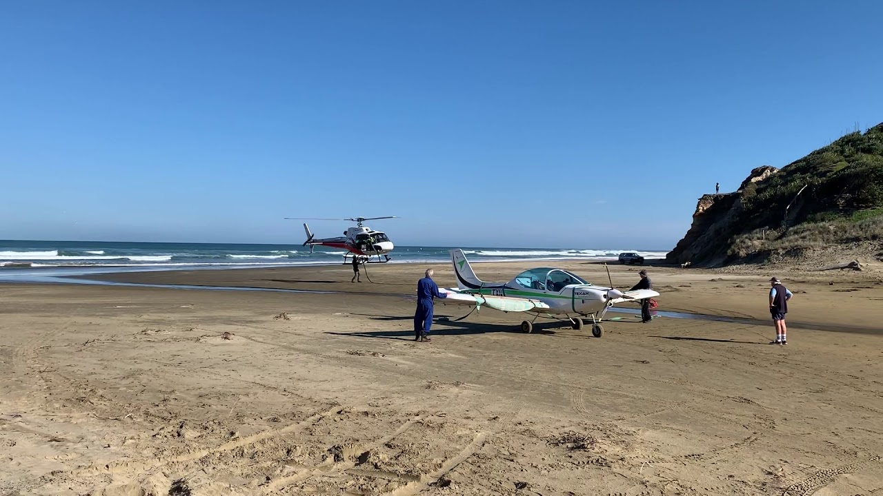 Helicopter picking up Texan plane that landed on the beach