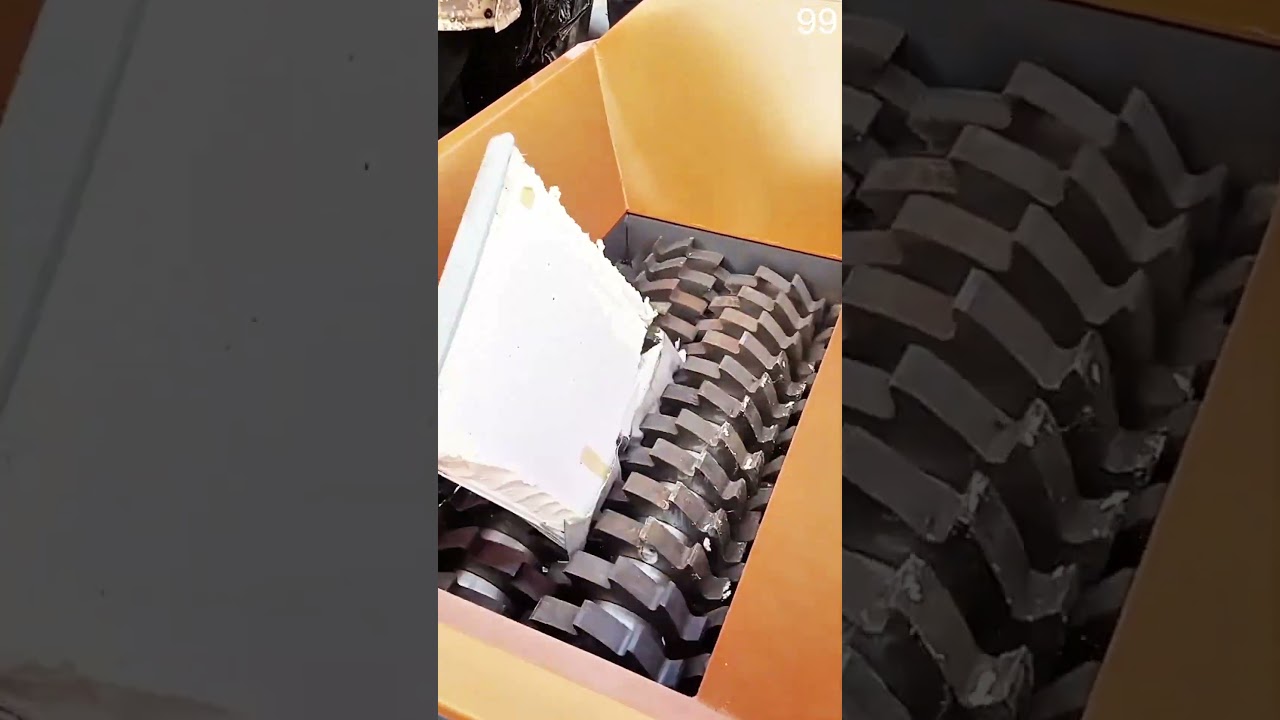 Orange shredder blades bite, composite panel torn apart into foam and metal fragments