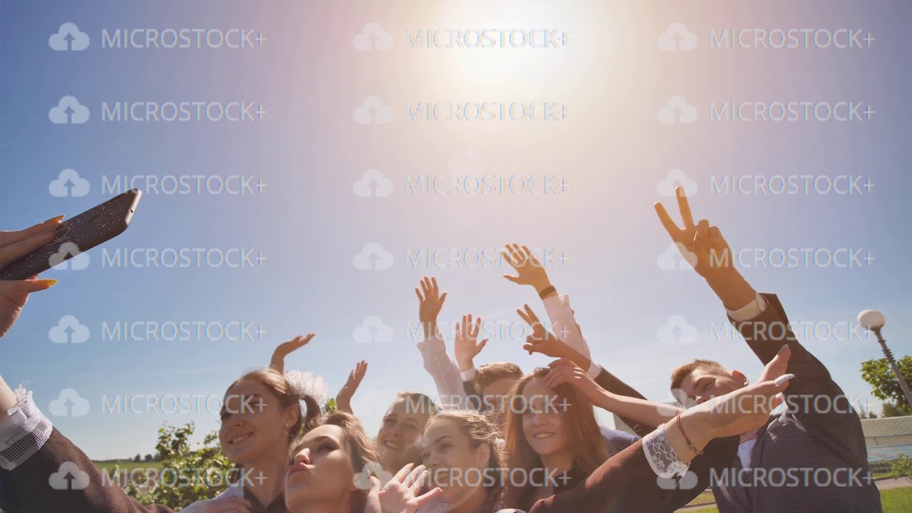 Happy high school graduates take a selfie on a sunny day.