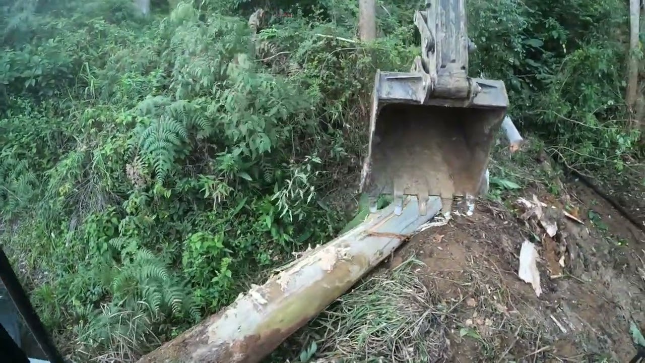Escavadeira colocando tubo e abrindo estrada com muita pedra