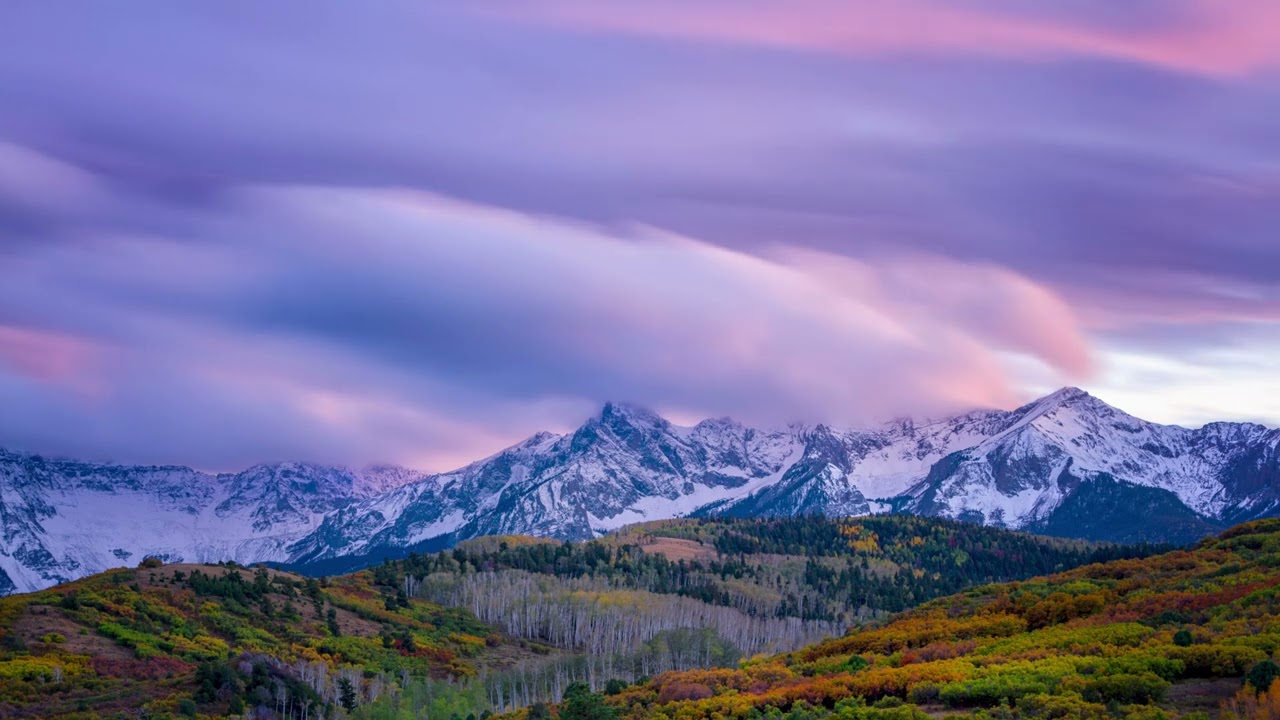 Snow Covered Mountain Range Meadow Under Beautiful Purple Cloudy Sunrise Sky Background Motion Loop