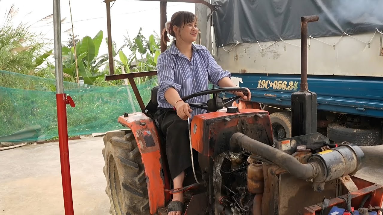 The girl repairs and restores the engine of a broken tractor.