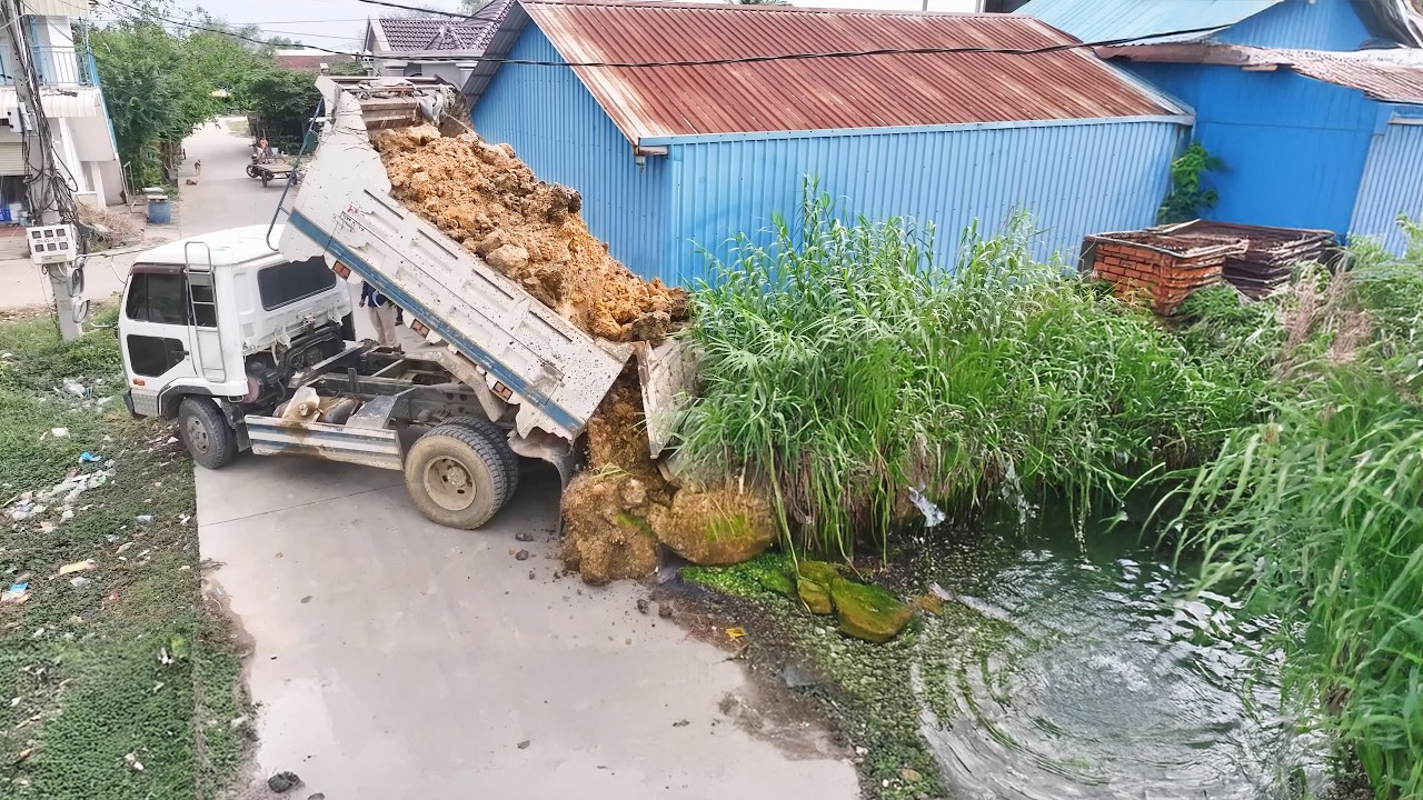 Starting project with a Komat'Su D20P bulldozer, pushing soil with a 5-ton truck into the water