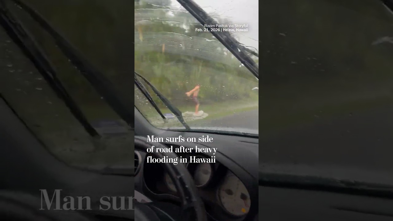Man surfs on side of road after heavy flooding in Hawaii