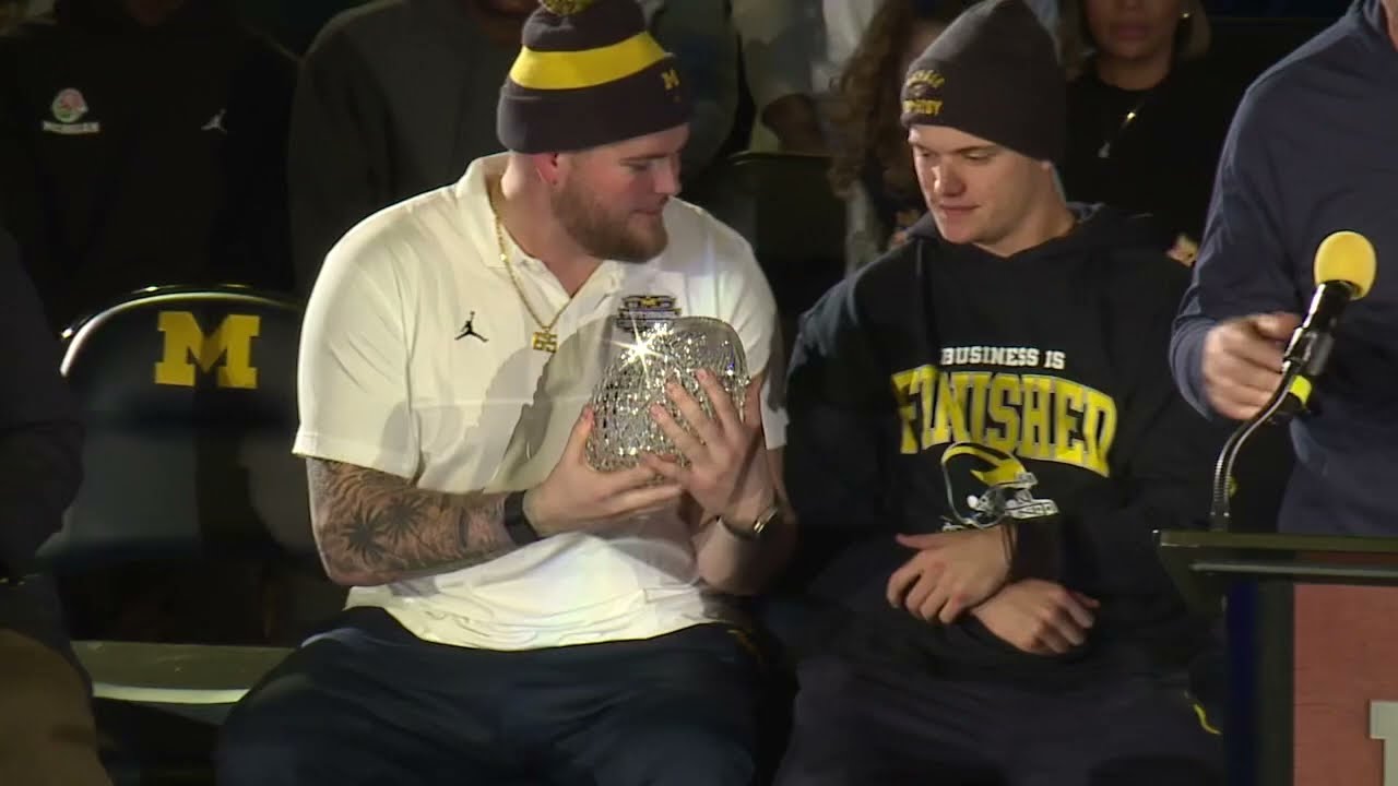 Michigan’s JJ McCarthy throws $30,000 crystal Coaches’ Trophy to Mike Sainristil on stage