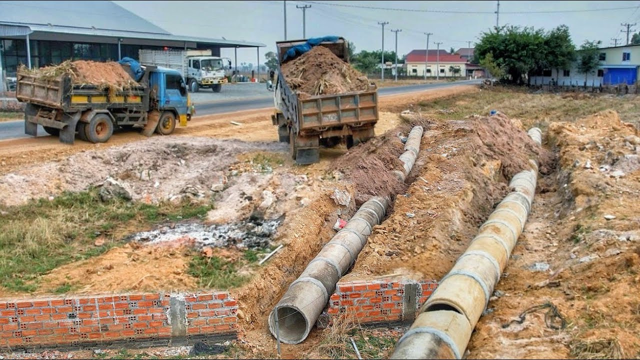 Dropping soil to bury drainage next to the road. Drivers passing by must be very careful.