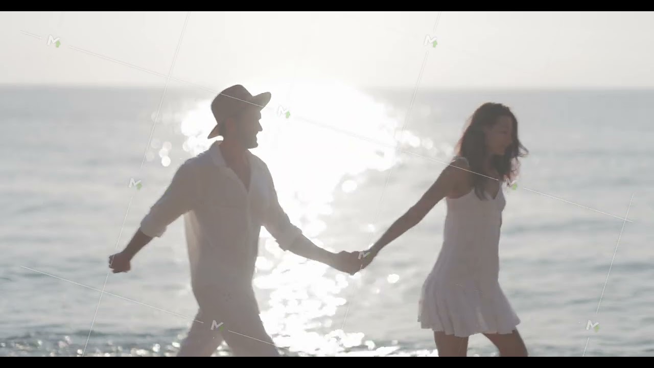 Happy Couple Walking Hand in Hand on the Beach at Sunset