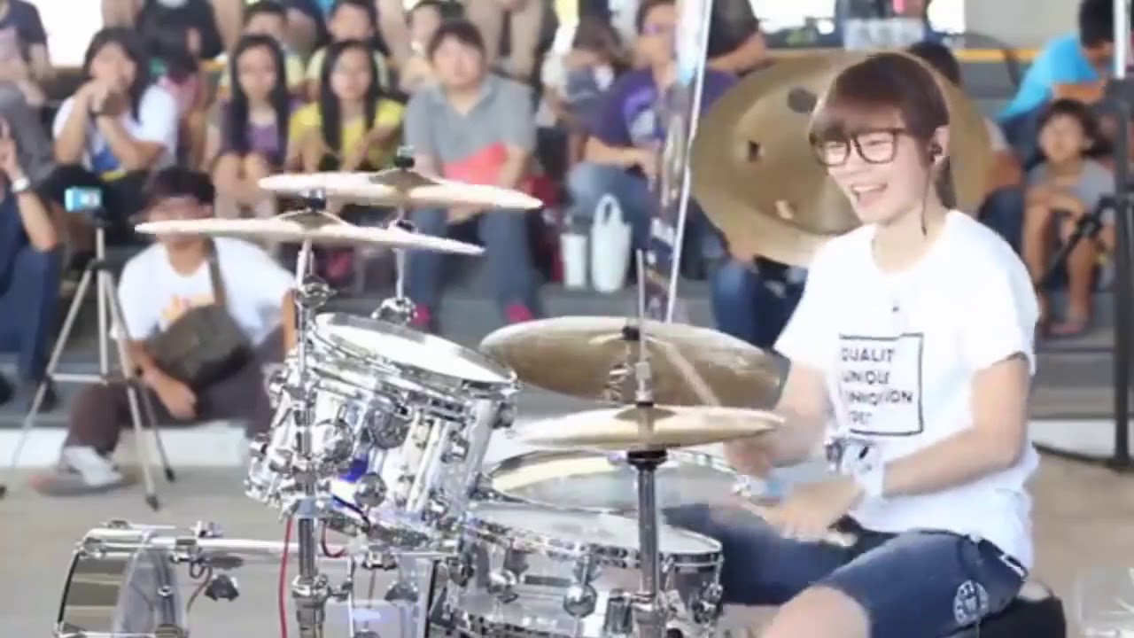 A cute girl playing drums in public walkway