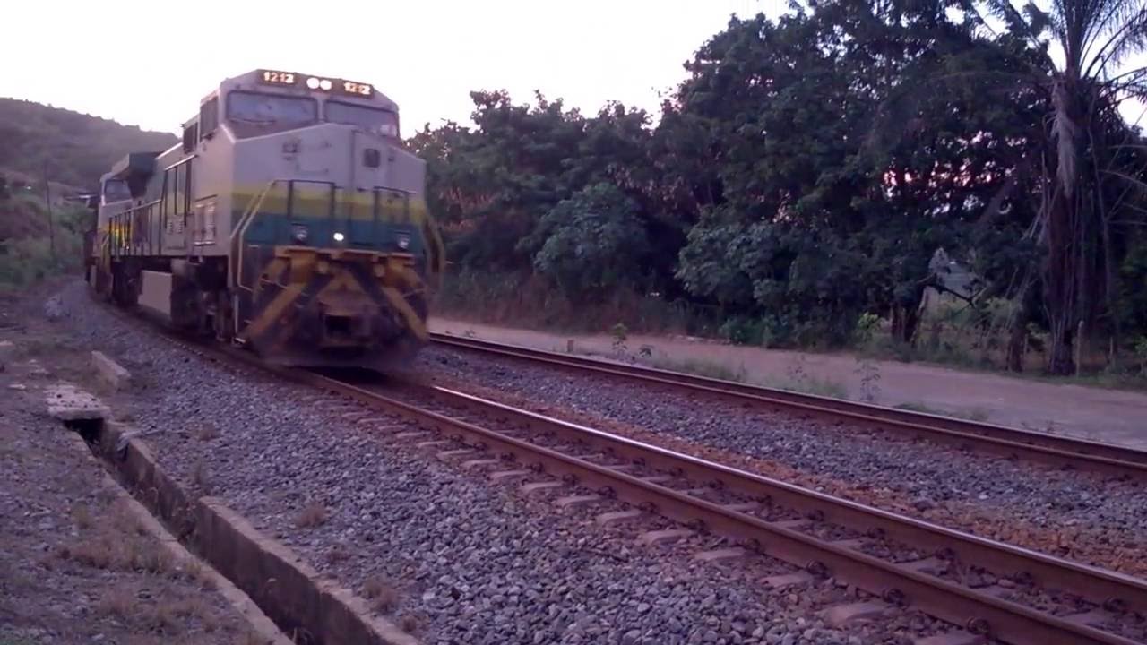 Trem de ferro parando para a troca de maquinista quando outro cruza velozmente.
