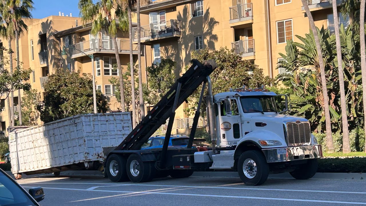 Peterbilt roll off truck dropping off an empty dumpster and picking up a full one at a construction 