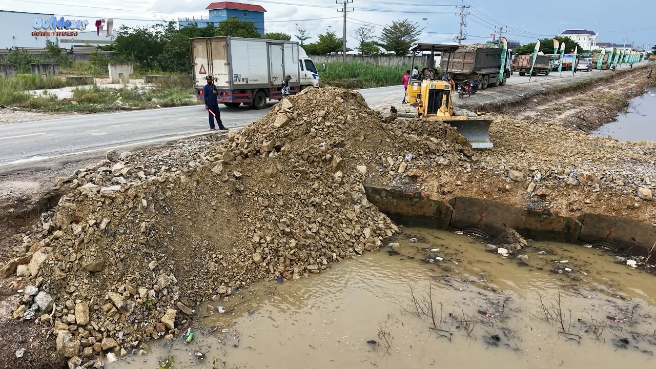 Skillfully Processing Filling Up Land By Heavy Bulldozer Push Soil Next To Canal With Dump Trucks